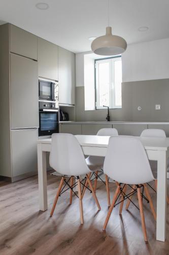 a kitchen with a white table and white chairs at Casa na Aldeia 1º Andar in Arcos de Valdevez