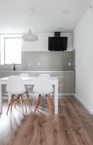 a kitchen with a table and two white chairs at Casa na Aldeia 1º Andar in Arcos de Valdevez