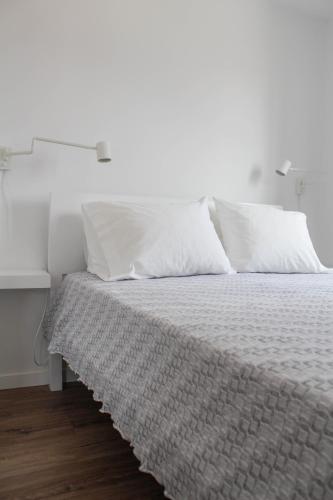 1 cama con sábanas blancas y almohadas en una habitación en Casa na Aldeia 1º Andar, en Arcos de Valdevez