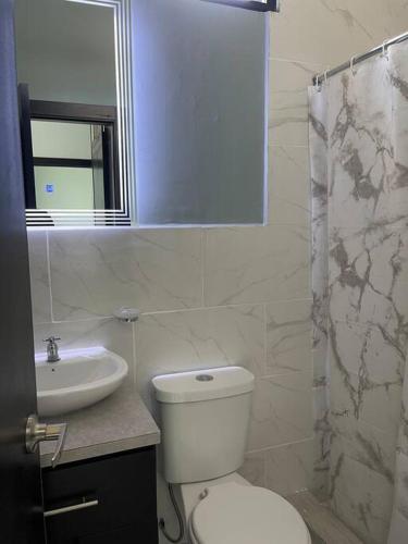 een witte badkamer met een toilet en een wastafel bij Hermosa casa en Salinas! in Salinas