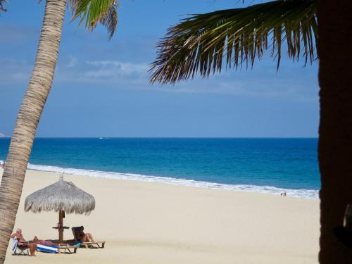 people sitting on the beach under an umbrella at Beachfront condo in Los Cabos, Mexico in San José del Cabo