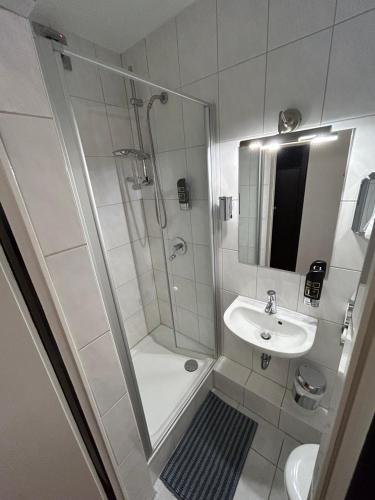 uma casa de banho branca com um chuveiro e um lavatório. em WestEnd#103 em Frankfurt am Main