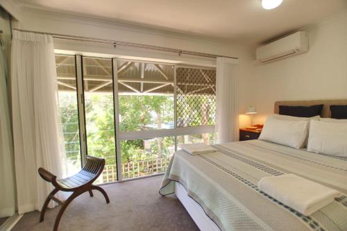 ein Schlafzimmer mit einem Bett, einem Stuhl und einem Fenster in der Unterkunft Raintrees Moffat Beach in Caloundra