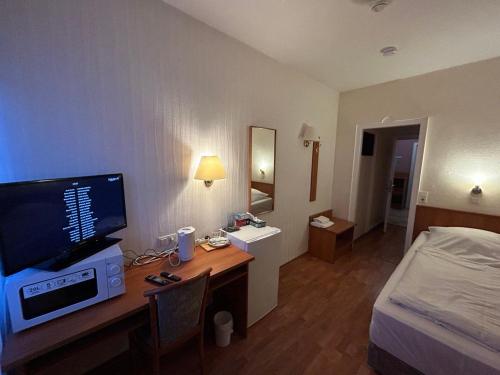 um quarto de hotel com uma secretária, uma televisão e uma cama em WestEnd#202 em Frankfurt am Main