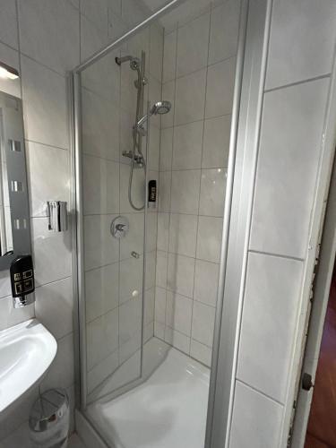 um chuveiro com uma porta de vidro ao lado de um lavatório em WestEnd#202 em Frankfurt am Main