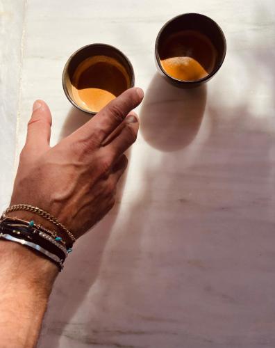 a hand reaching for two cups of coffee on a table at ROMEO AND JULIO SUMMER HOUSE in Mýkonos City