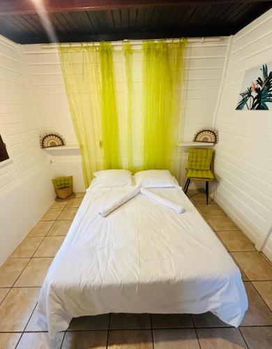 a bed in a room with a yellow curtain at Villa Réséda in Sainte-Anne