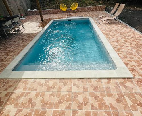 a swimming pool with two chairs and a table at Villa Réséda in Sainte-Anne