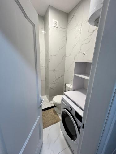 a white bathroom with a toilet and a door at Durres Lovely Apartment in Durrës