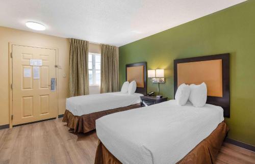ein Hotelzimmer mit 2 Betten und grünen Wänden in der Unterkunft Extended Stay America Suites - St Louis - Westport - East Lackland Rd in Maryland Heights