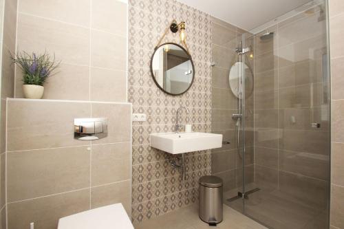 ein Bad mit einer Dusche, einem Waschbecken und einem Spiegel in der Unterkunft strandnahes Haus mit Meerblick, gratis Nutzung vom AHOI Erlebnisbad und Sauna in Sellin - Sealodge Rügen in Göhren