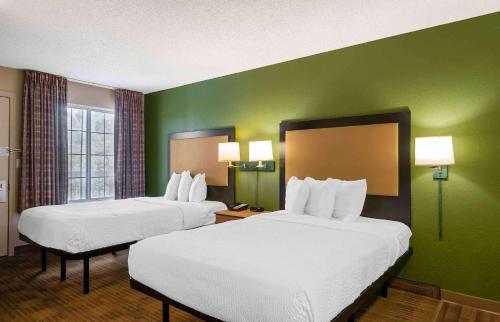 two beds in a hotel room with green walls at Extended Stay America Select Suites - Tampa - Brandon in Brandon
