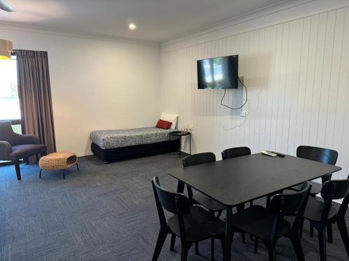 een kamer met een tafel, een bed en een televisie bij Longreach Motor Inn in Longreach