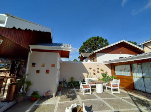 une terrasse d'une maison avec des chaises et une table dans l'établissement Mouton Blanc Campos do Jordão, à Campos do Jordão