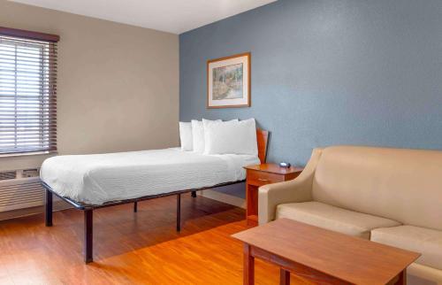 ウィルミントンにあるExtended Stay America Select Suites - Wilmington - Westのベッド1台とソファが備わる小さな客室です。