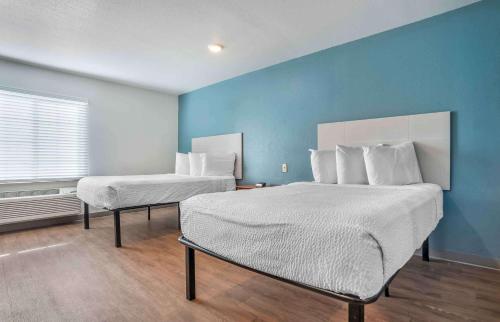 a bedroom with two beds and a blue wall at Extended Stay America Select Suites - Jackson - South in Byram