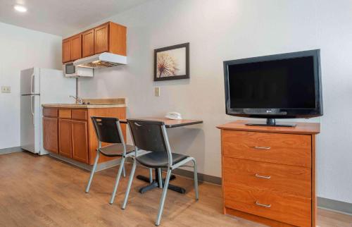 a kitchen with a desk with two chairs and a television at Extended Stay America Select Suites - Jackson - South in Byram