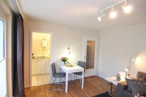 ein Wohnzimmer mit einem weißen Tisch und eine Küche in der Unterkunft Ferienwohnung Austernfischerin in Westerland