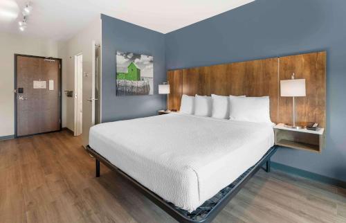 a bedroom with a large bed and a blue wall at Extended Stay America Suites - Huntsville - Madison in Madison