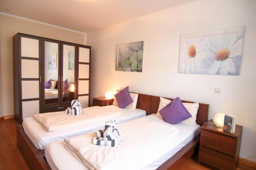 Cette chambre comprend 2 lits avec des oreillers violets et blancs. dans l'établissement Ferienwohnung Lena Bockelmann´s Hof (ebenerdig), à Westerland