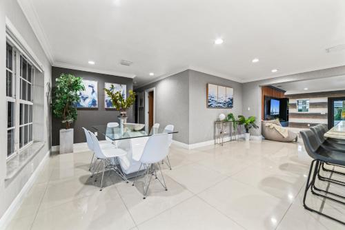 a dining room with a glass table and white chairs at Oasis with Pool Spa Games 5BR L21 in Miami Gardens