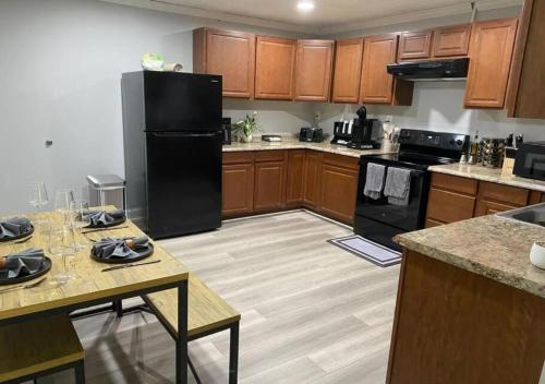 a kitchen with a black refrigerator and wooden cabinets at Modern 2BR Aparment near NC ZOO w Parking in Asheboro