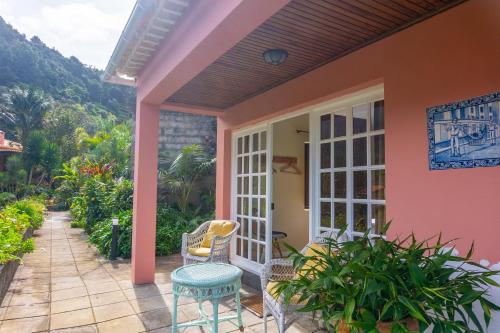 a porch of a pink house with a table and chairs at Madeira Surf Lodge in São Vicente