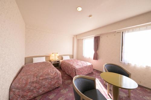 Main Hotel - Vacation STAY 82549 في مياكونوجو: غرفة فندقية بسريرين وطاولة وكراسي
