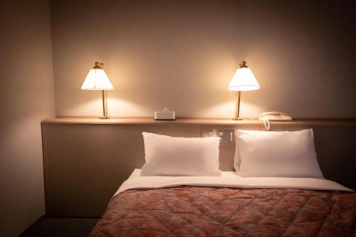 Una cama con dos lámparas encima. en Main Hotel - Vacation STAY 82550, en Miyakonojō