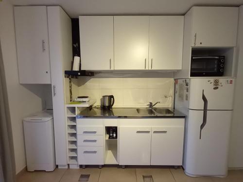 uma cozinha com armários brancos, um lavatório e um frigorífico em -BLA BLA... em Ushuaia