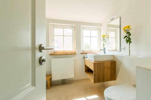 a white bathroom with a sink and a mirror at Haus Wiesenweite in Born