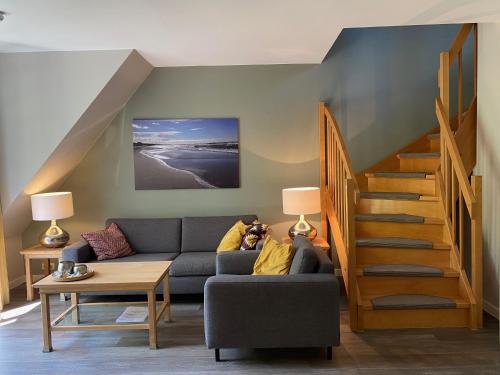 ein Wohnzimmer mit einer Couch und einer Treppe in der Unterkunft Haus Kranich App 422 in Dierhagen
