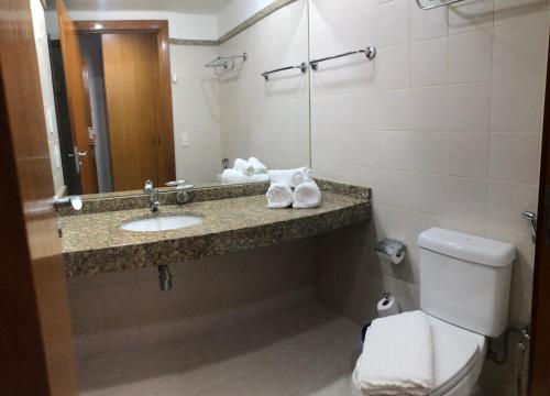 a bathroom with a sink and a toilet and a mirror at Flat 315 - Comfort Hotel Taguatinga in Brasília