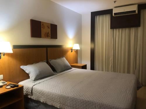 a bedroom with a bed and two lamps and a window at Flat 315 - Comfort Hotel Taguatinga in Brasilia