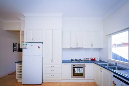 a kitchen with white cabinets and a white refrigerator at Twilight Villa - 3 bedroom house in Box Hill in Box Hill