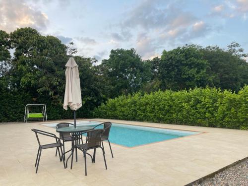 a table with chairs and an umbrella next to a pool at CASA CAMPESTRE VILLALUPO in Villavicencio