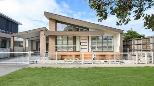a house with a white fence in front of it at Villa Marina - Modern Waterfront Escape in Lakes Entrance