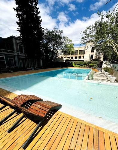 a wooden deck with a bench next to a swimming pool at Departamento Elegante en Torre Leloir in Villa Marini