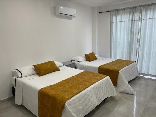 two beds in a room with a window at CASA CAMPESTRE VILLALUPO in Villavicencio