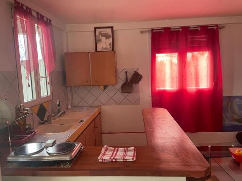 a kitchen with red curtains and a sink and a counter at Villa yoyo poirier in Sainte-Anne
