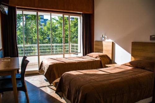 a hotel room with two beds and a window at Grand Hotel Rio Cuarto in Río Cuarto
