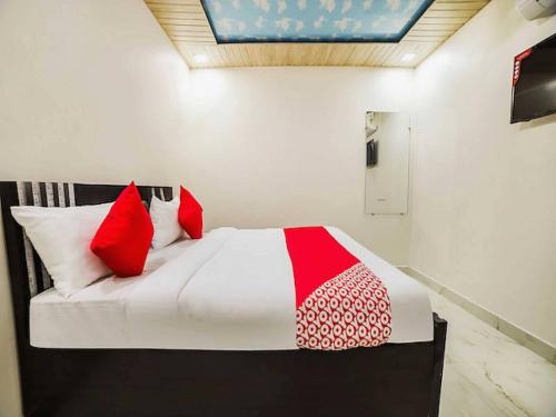 a bedroom with a bed with red and white pillows at OYO Hotel silver stone in Najafgarh