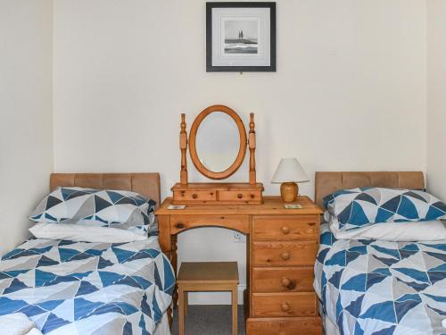 een slaapkamer met 2 bedden en een dressoir met een spiegel bij Totland in Wootton Bridge