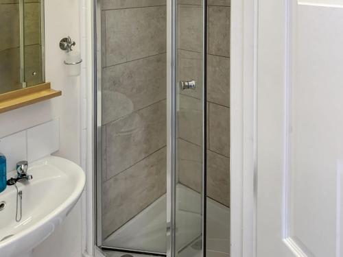 a shower with a glass door next to a sink at Totland in Wootton Bridge