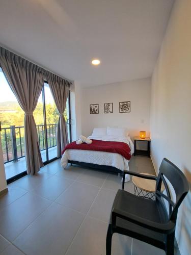a bedroom with a bed and a chair and a window at Guatapé Country House Hotel in Guatapé