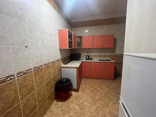 a small kitchen with red cabinets and a white refrigerator at Coov AlAnbarya in Al ‘Awālī