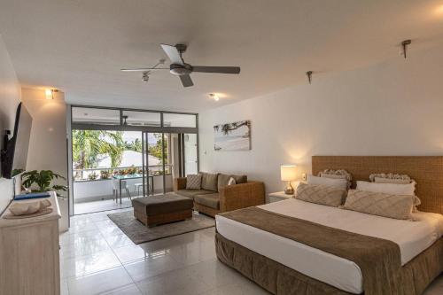 a bedroom with a bed and a living room at Club Tropical Resort with Onsite Reception & Check In in Port Douglas