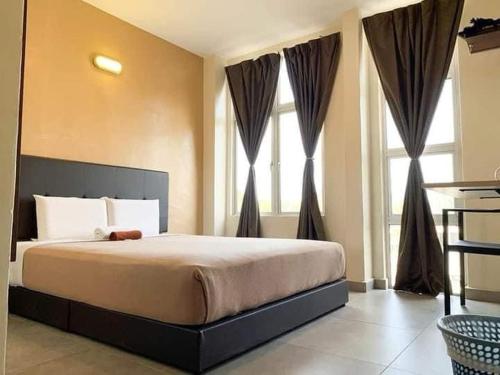 a bedroom with a large bed in front of windows at Dramayu Hotel in Kuantan
