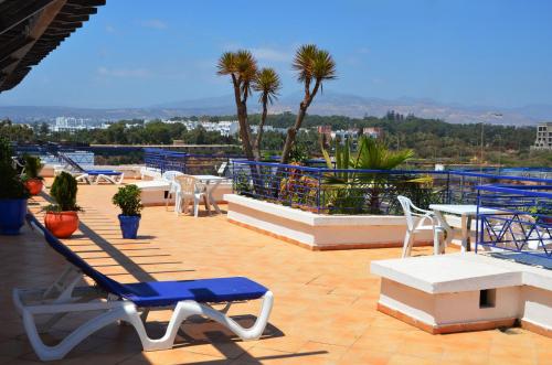 a patio with blue and white chairs and tables at Golden Beach Appart'hotel in Agadir
