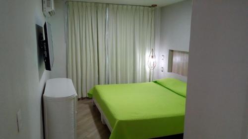 Un dormitorio con una cama verde y una ventana en Hotel Marina Puerto Dorado - Todo Incluido, en Manzanillo